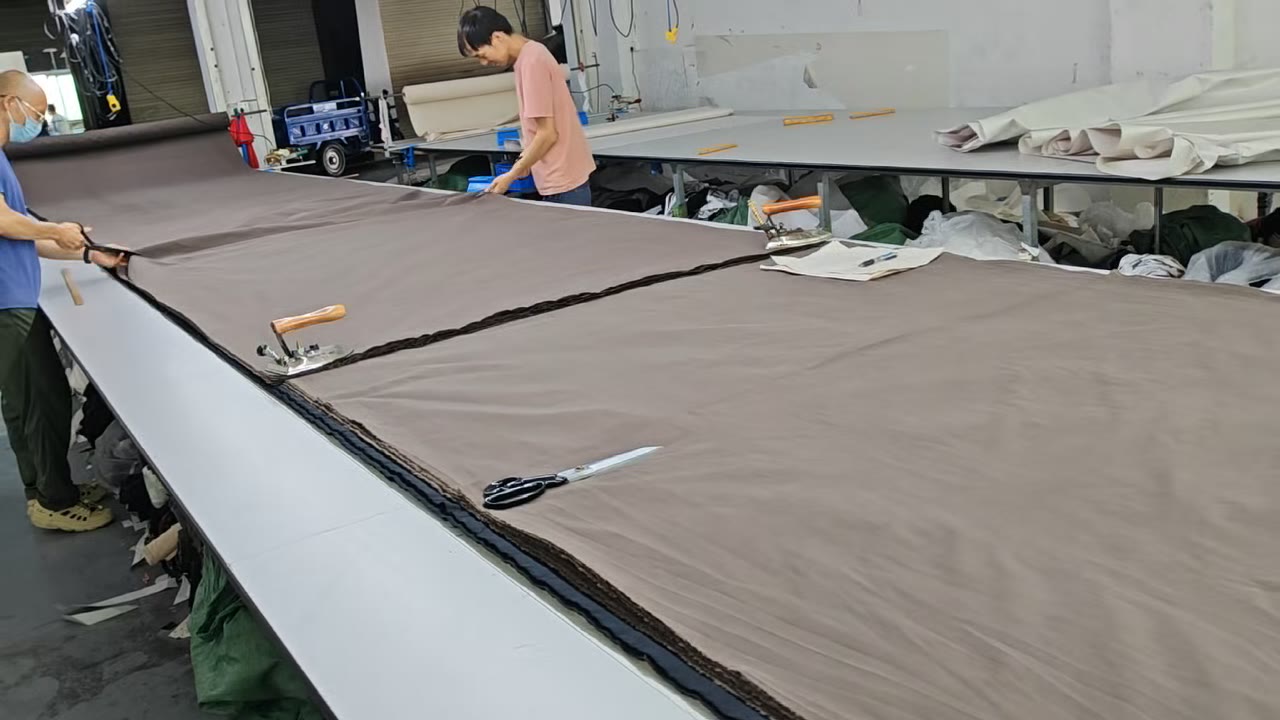 Workers spreading fabric across a garment cutting table